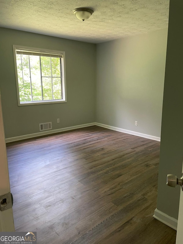 unfurnished room featuring a textured ceiling and dark hardwood / wood-style flooring