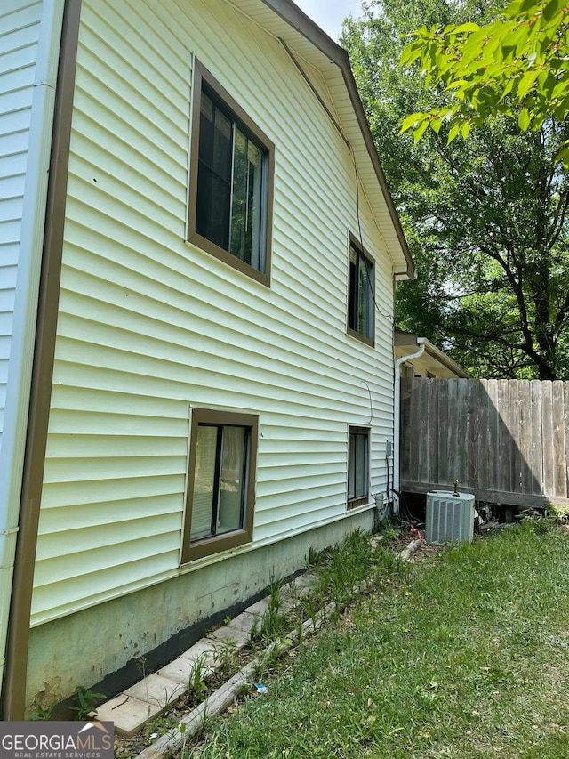 view of property exterior with a lawn and central AC