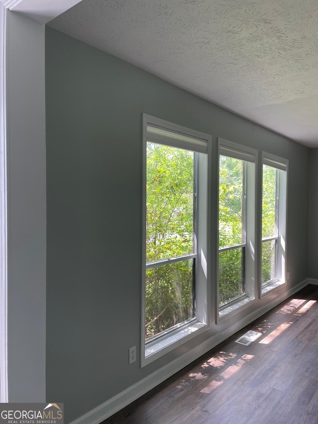 spare room featuring dark hardwood / wood-style flooring and a textured ceiling