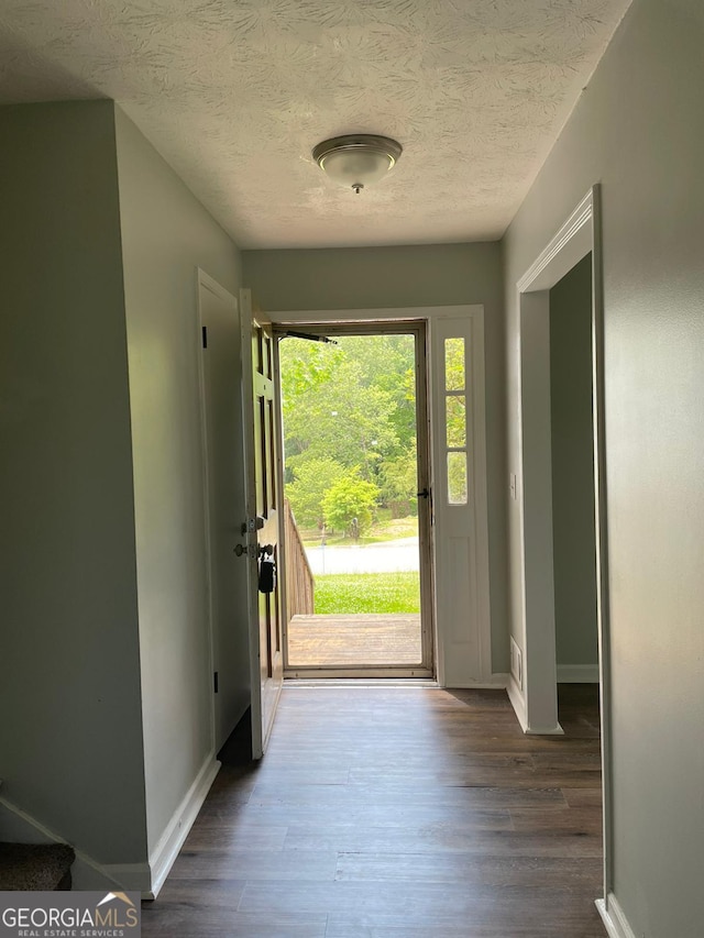 doorway featuring a textured ceiling and dark hardwood / wood-style flooring