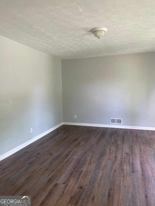 empty room featuring dark wood-type flooring and a textured ceiling