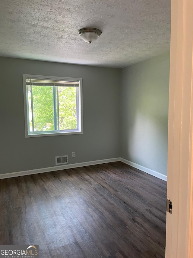 unfurnished room featuring a textured ceiling and dark hardwood / wood-style floors