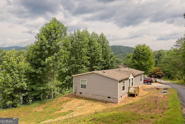 view of side of home with a mountain view and a lawn