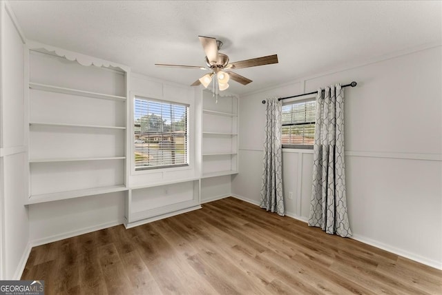 spare room with ceiling fan, wood-type flooring, ornamental molding, and a textured ceiling