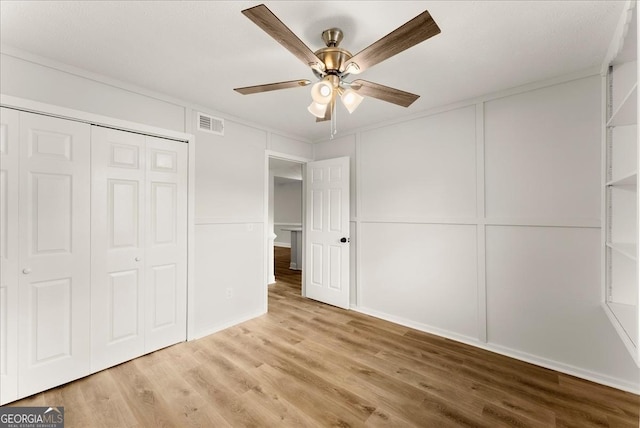 unfurnished bedroom featuring light wood-type flooring, ceiling fan, ornamental molding, and a closet