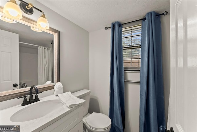 bathroom featuring a textured ceiling, toilet, and vanity