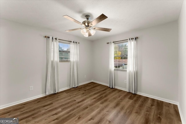 unfurnished room with ceiling fan, a wealth of natural light, and dark hardwood / wood-style floors