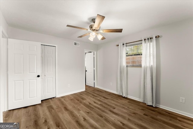 unfurnished bedroom featuring ceiling fan, a closet, and dark hardwood / wood-style flooring