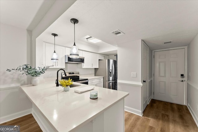 kitchen featuring white cabinets, kitchen peninsula, and stainless steel appliances