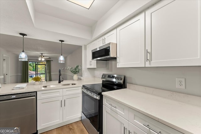 kitchen featuring ceiling fan, stainless steel appliances, decorative light fixtures, white cabinets, and sink