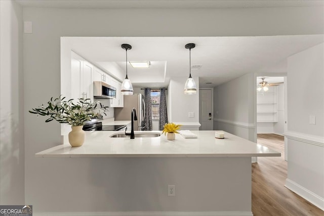 kitchen featuring ceiling fan, kitchen peninsula, sink, hanging light fixtures, and stainless steel appliances