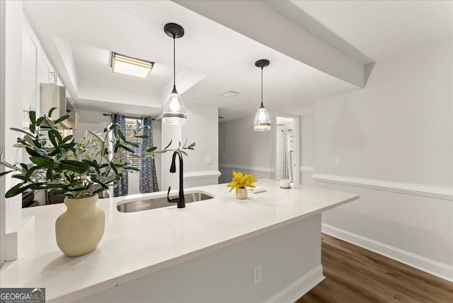 kitchen featuring light stone countertops, decorative light fixtures, dark hardwood / wood-style floors, and sink