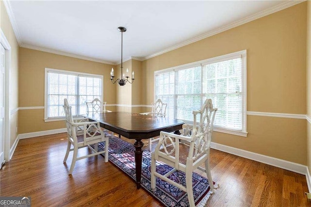 dining room with an inviting chandelier, ornamental molding, a healthy amount of sunlight, and hardwood / wood-style floors