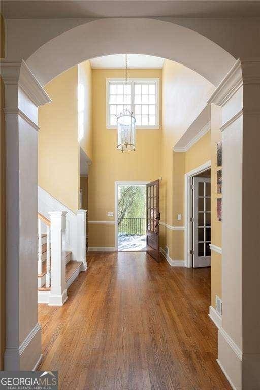 unfurnished living room with a high ceiling, hardwood / wood-style floors, and a notable chandelier