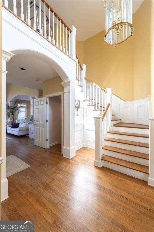 entryway with decorative columns, hardwood / wood-style flooring, and an inviting chandelier