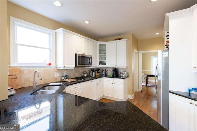 kitchen featuring backsplash, dark stone countertops, sink, appliances with stainless steel finishes, and white cabinets