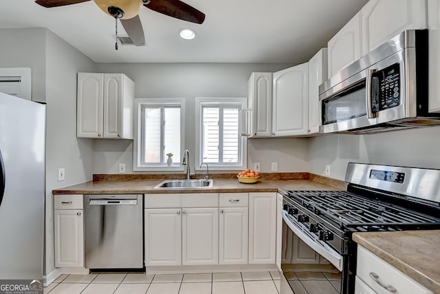 kitchen featuring white cabinets, stainless steel appliances, sink, light tile patterned flooring, and ceiling fan