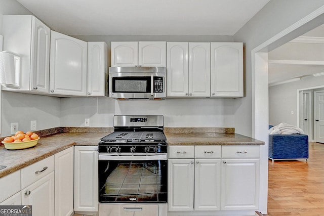 kitchen featuring white cabinets, light hardwood / wood-style flooring, ornamental molding, and appliances with stainless steel finishes