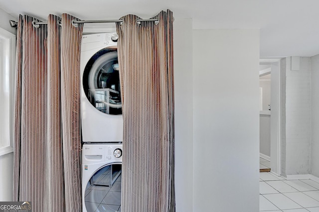 laundry room featuring stacked washer / dryer and light tile patterned flooring