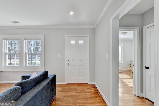 entryway with light hardwood / wood-style flooring and crown molding