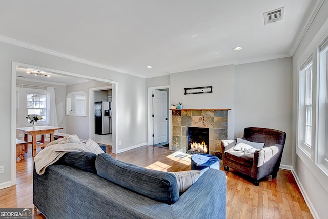 living room with hardwood / wood-style floors, crown molding, and a fireplace