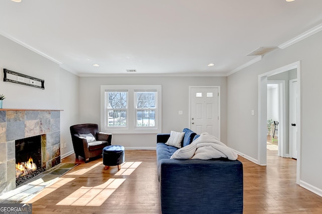 living room with hardwood / wood-style flooring, ornamental molding, and a tile fireplace