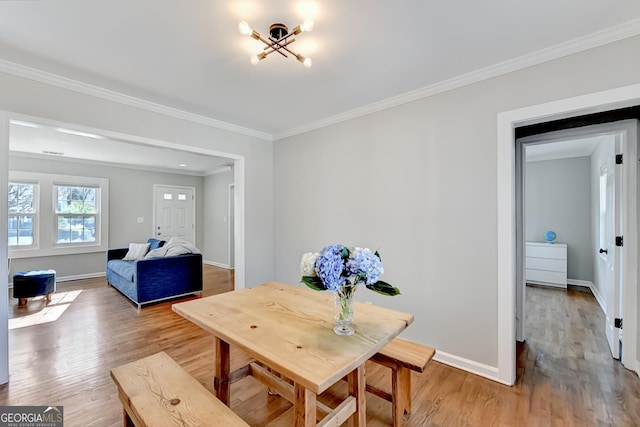 dining space with ornamental molding and light hardwood / wood-style flooring