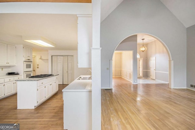 kitchen featuring light hardwood / wood-style floors, a center island, double oven, white cabinets, and sink