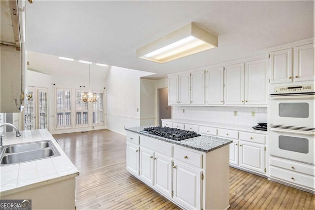 kitchen with white cabinets, double oven, sink, and a kitchen island