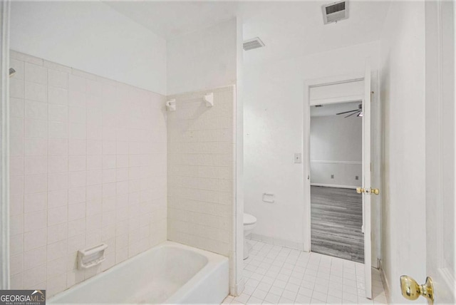 bathroom with toilet, tiled shower / bath combo, and tile patterned floors