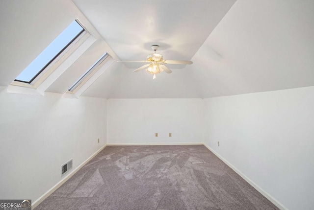 additional living space featuring ceiling fan, vaulted ceiling with skylight, and carpet flooring