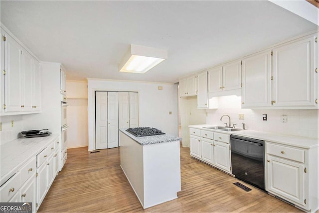 kitchen featuring sink, dishwasher, white cabinets, and a center island