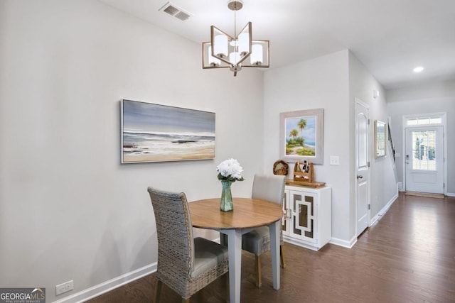 dining room with dark wood-type flooring and a notable chandelier