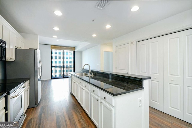 kitchen featuring dark hardwood / wood-style floors, white cabinetry, a center island with sink, and sink