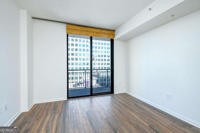 spare room featuring floor to ceiling windows and dark hardwood / wood-style flooring