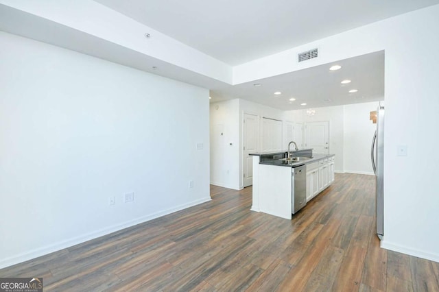 kitchen featuring a center island with sink, sink, dark wood-type flooring, stainless steel appliances, and white cabinets