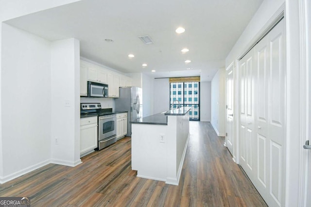 kitchen with white cabinets, a kitchen island with sink, appliances with stainless steel finishes, and dark hardwood / wood-style floors