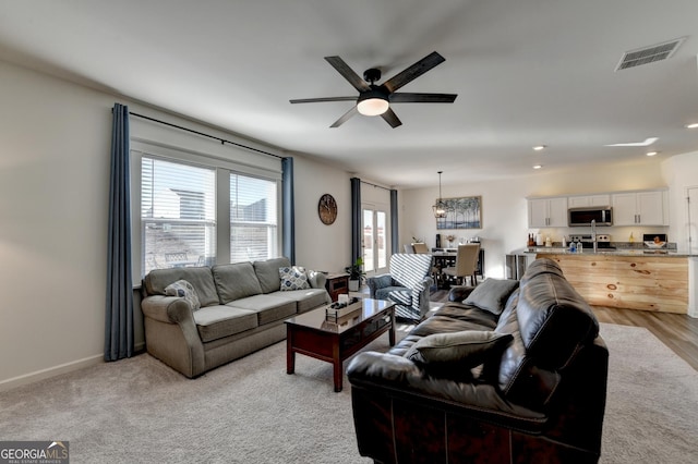 living room featuring light colored carpet and ceiling fan