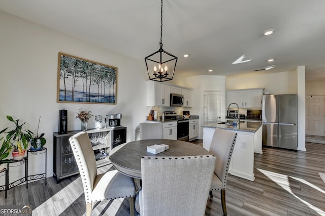 dining room with dark hardwood / wood-style floors, sink, and a notable chandelier