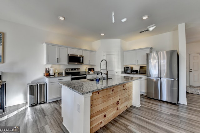 kitchen featuring white cabinetry, stainless steel appliances, light stone countertops, and sink