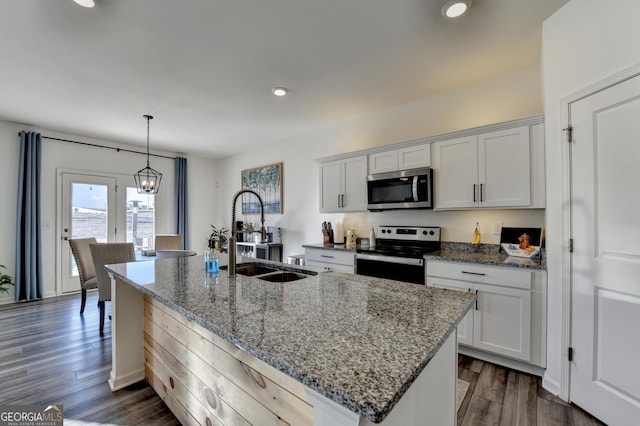 kitchen with white cabinetry, light stone counters, a kitchen island with sink, and appliances with stainless steel finishes