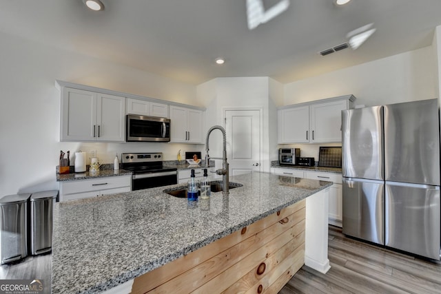 kitchen with light stone counters, appliances with stainless steel finishes, sink, and white cabinets