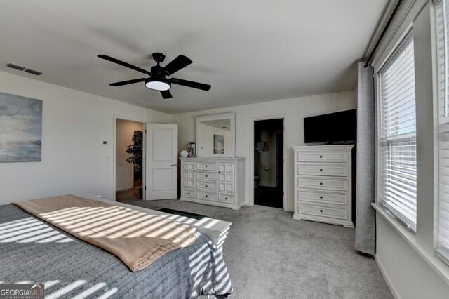 carpeted bedroom with ensuite bath and ceiling fan