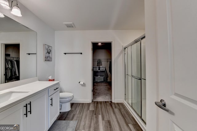 bathroom featuring vanity, wood-type flooring, toilet, and walk in shower