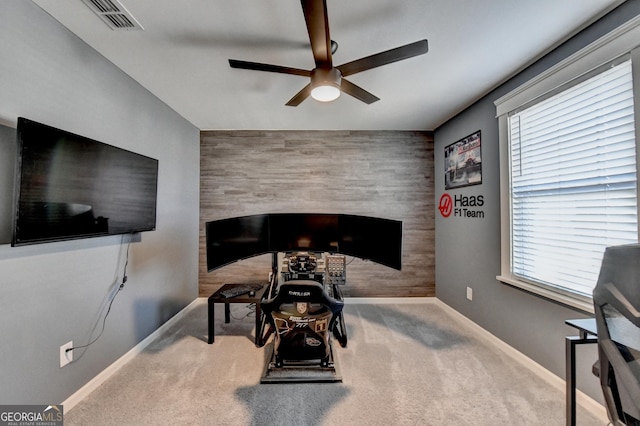 home office featuring ceiling fan, wooden walls, and light carpet