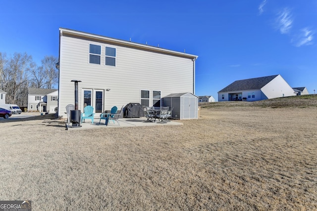 rear view of property featuring a storage unit, a yard, and a patio area