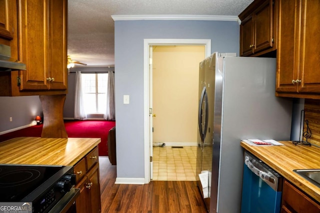 kitchen with ceiling fan, appliances with stainless steel finishes, wooden counters, and ornamental molding