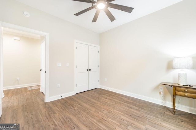 unfurnished bedroom with ceiling fan, hardwood / wood-style floors, and a closet