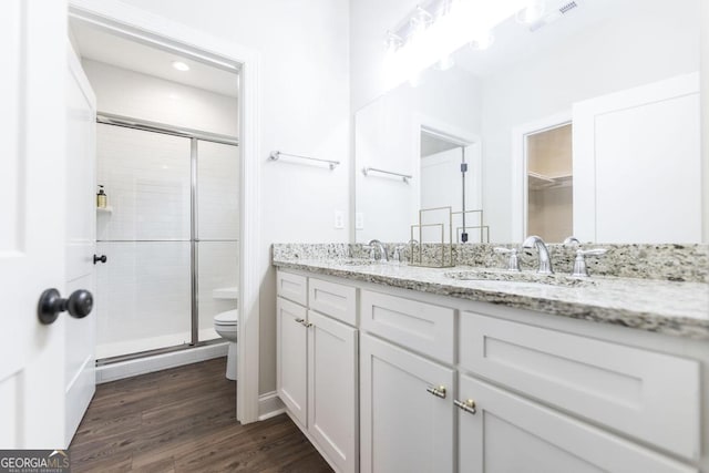 bathroom with vanity, hardwood / wood-style flooring, a shower with shower door, and toilet