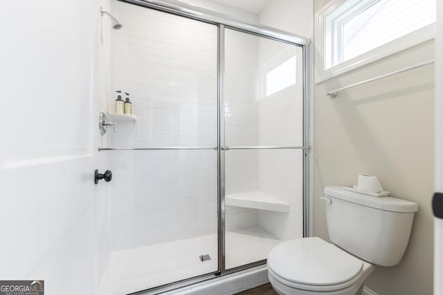 bathroom featuring a shower with shower door and toilet